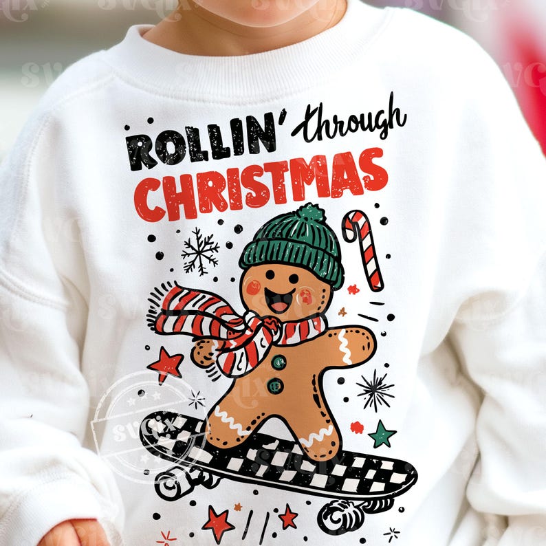 May include: White sweatshirt featuring a gingerbread man on a skateboard, wearing a green hat and a red and white scarf. The text "ROLLIN' through CHRISTMAS" is above the gingerbread man. The design includes snowflakes, stars, and a candy cane.
