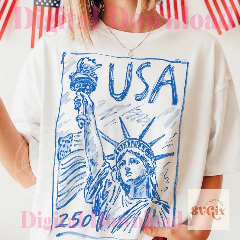 K&ouml;nnte beinhalten: Wei&szlig;es T-Shirt mit einer blauen Skizze der Freiheitsstatue und dem Wort "USA". Das Design beinhaltet die amerikanische Flagge und die Fackel. Das Shirt ist ein l&auml;ssiger Stil.
