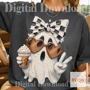 May include: A charcoal gray t-shirt featuring a textured, painterly graphic of a white ghost wearing a black and white checkered bow, brown heart-shaped sunglasses, and holding a coffee cup while making a peace sign with one hand.