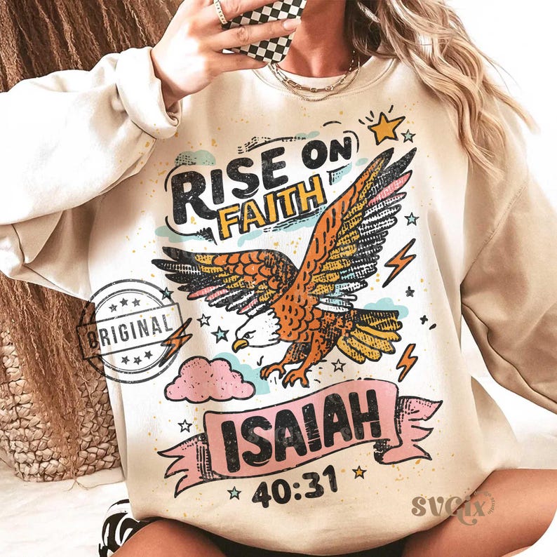 Puede incluir: Sudadera beige con un dise&ntilde;o gr&aacute;fico de un &aacute;guila, las palabras "RISE ON FAITH" e "ISAIAH 40:31". El dise&ntilde;o incluye estrellas, rayos y una nube rosa. La palabra "ORIGINAL" est&aacute; estampada en el lado izquierdo.