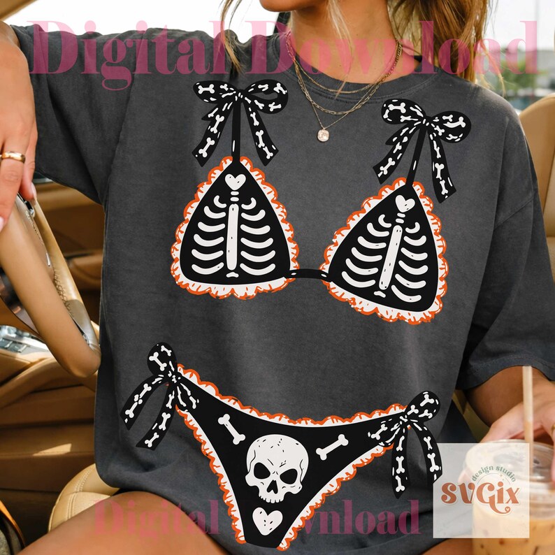 Peut inclure: Un t-shirt gris anthracite avec une impression graphique repr&eacute;sentant un bikini noir orn&eacute; d'un motif de cage thoracique squelettique blanche sur le haut et d'un cr&acirc;ne avec des os sur le bas, avec des bords volant&eacute;s orange et des liens noirs.