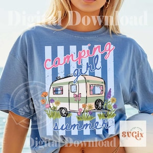 May include: Pale blue t-shirt featuring a camping trailer graphic with the words "Camping Girl Summer." The trailer is green and white with pink details, surrounded by flowers. Text is pink and blue.