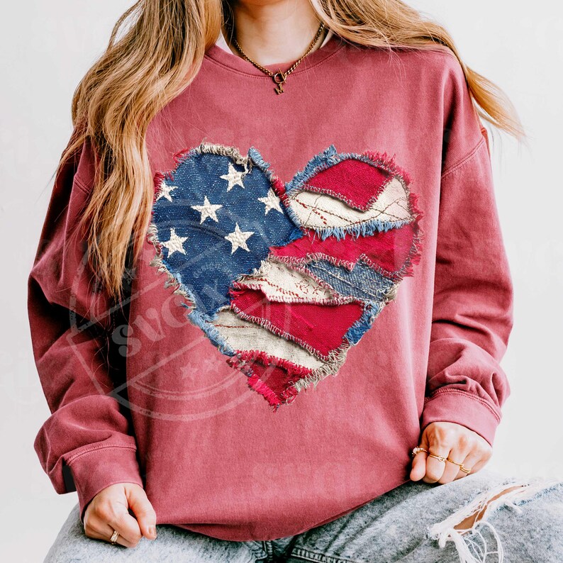 May include: A maroon sweatshirt with a heart-shaped design made from patches of denim and red and white fabric. The denim patch features white stars, reminiscent of the American flag. The heart's edges are frayed, giving it a rustic appearance.
