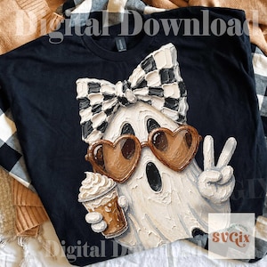 May include: A black t-shirt featuring a white ghost graphic with a thick, textured paint effect. The ghost wears a black and white checkered bow, brown heart-shaped sunglasses, and holds a coffee cup while making a peace sign gesture.