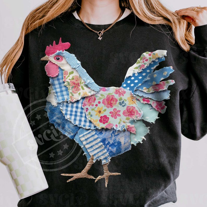 May include: Black sweatshirt featuring a patchwork rooster design. The rooster is made of various patterned fabrics, including floral, gingham, and polka dots, in shades of blue, pink, and white. The rooster has a red comb and wattle.