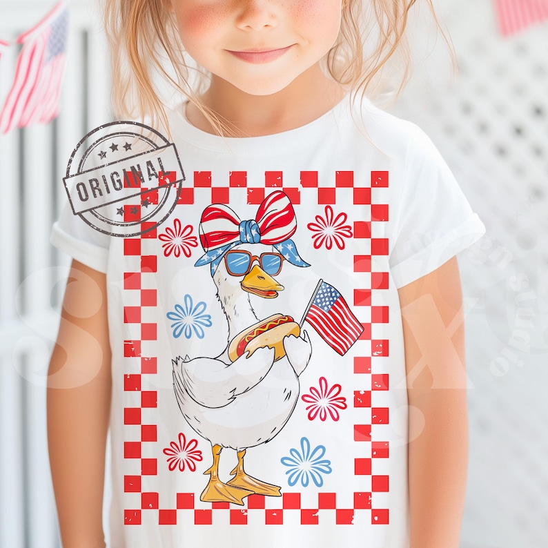 May include: A white t-shirt with a red, white, and blue checkered background. A cartoon goose wearing a red, white, and blue bandana and sunglasses is holding a hot dog and an American flag. The goose is surrounded by red, white, and blue fireworks.