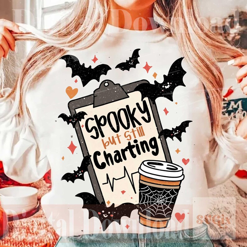 May include: A white sweatshirt featuring a graphic of a clipboard with the text "Spooky but Still Charting" above a heartbeat line. The design includes a coffee cup with a spiderweb pattern, black bats, and small orange and red hearts and stars.