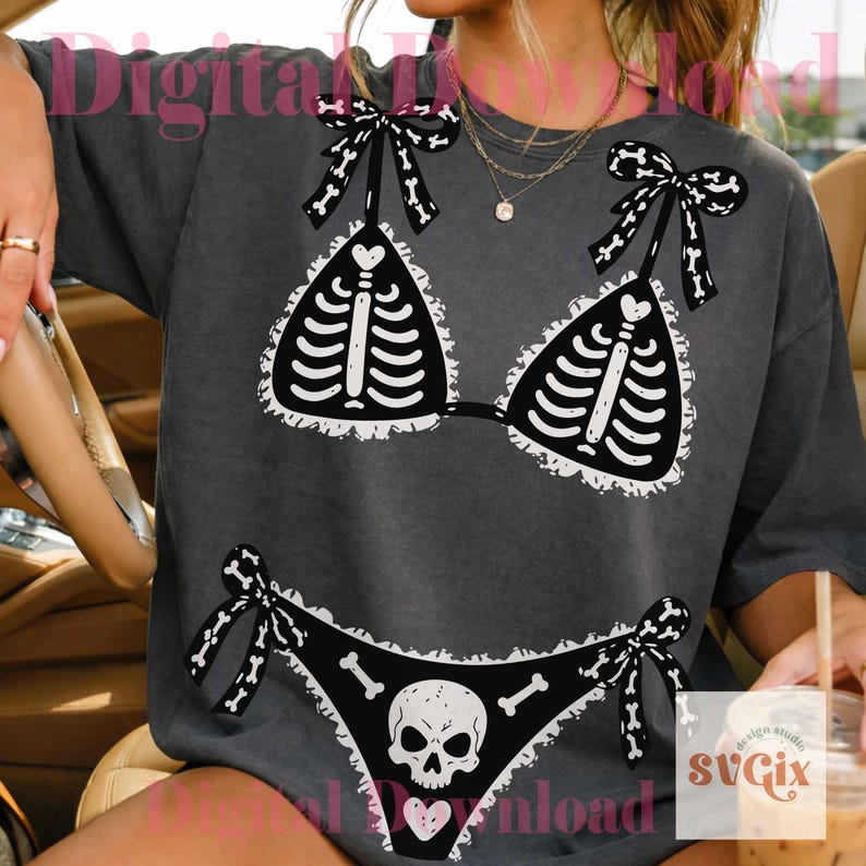 Peut inclure: Un t-shirt gris anthracite avec une impression graphique repr&eacute;sentant un ensemble de bikini, avec un motif de cage thoracique sur le haut et un cr&acirc;ne avec des os sur le bas. L'imprim&eacute; inclut des bordures en dentelle blanche et des n&oelig;uds.