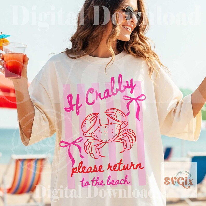 May include: Cream-colored t-shirt with a pink crab graphic and the text "If Crabby please return to the beach." The design includes pink vertical stripes and bows. The shirt is a casual beachwear item.