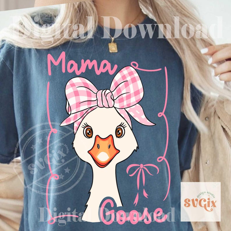 Pode incluir: Camiseta azul com um desenho de ganso de desenho animado usando um la&ccedil;o e uma faixa xadrez rosa e branca. As palavras "Mama Goosed" est&atilde;o escritas em rosa. O desenho &eacute; emoldurado por linhas rosa e uma pequena fita.
