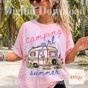 May include: Pale pink t-shirt with a camping design. The shirt displays a camper graphic with the words "camping girl summer" in a whimsical font. The camper is adorned with flowers and a bow.