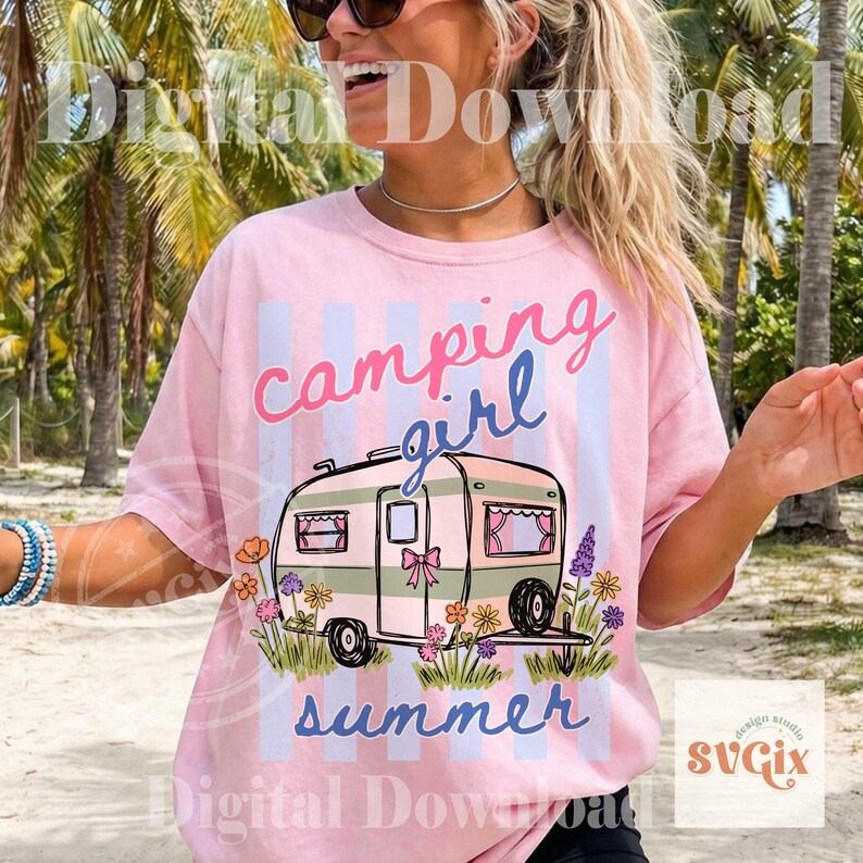 May include: Pale pink t-shirt with a camping design. The shirt displays a camper graphic with the words "camping girl summer" in a whimsical font. The camper is adorned with flowers and a bow.