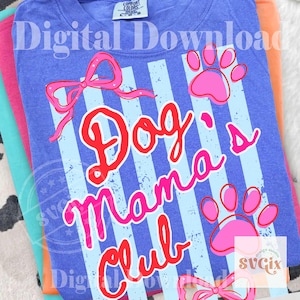 May include: A stack of t-shirts in shades of blue, pink, and orange. The top shirt is blue with a design that says "Dog Mama Club" in red and pink, with paw prints and a bow.