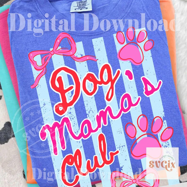 May include: A stack of t-shirts in shades of blue, pink, and orange. The top shirt is blue with a design that says "Dog Mama Club" in red and pink, with paw prints and a bow.
