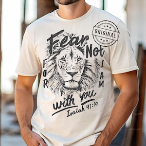 Puede incluir: Camiseta color crema con un detallado rostro de le&oacute;n en blanco y negro. La camiseta tiene el texto "Fear Not, I Am with you Isaiah 41:10" en negrita, con un sello "ORIGINAL".