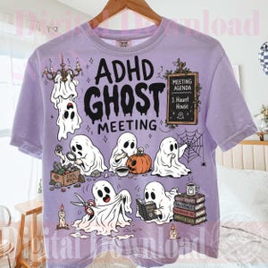 Może przedstawiać: Jasnofioletowy t-shirt z nadrukiem graficznym i napisem "ADHD GHOST MEETING". Wzór przedstawia kilka białych duchów zajętych różnymi czynnościami, takimi jak czytanie, wycinanie dyni oraz oglądanie kamieni przy tablicy.