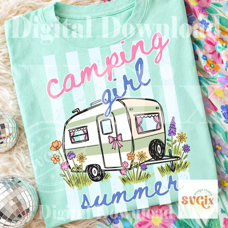 May include: A mint green t-shirt featuring a campervan graphic and the text "camping girl summer." The campervan is white and green with pink details, set against a striped background. Flowers surround the campervan.