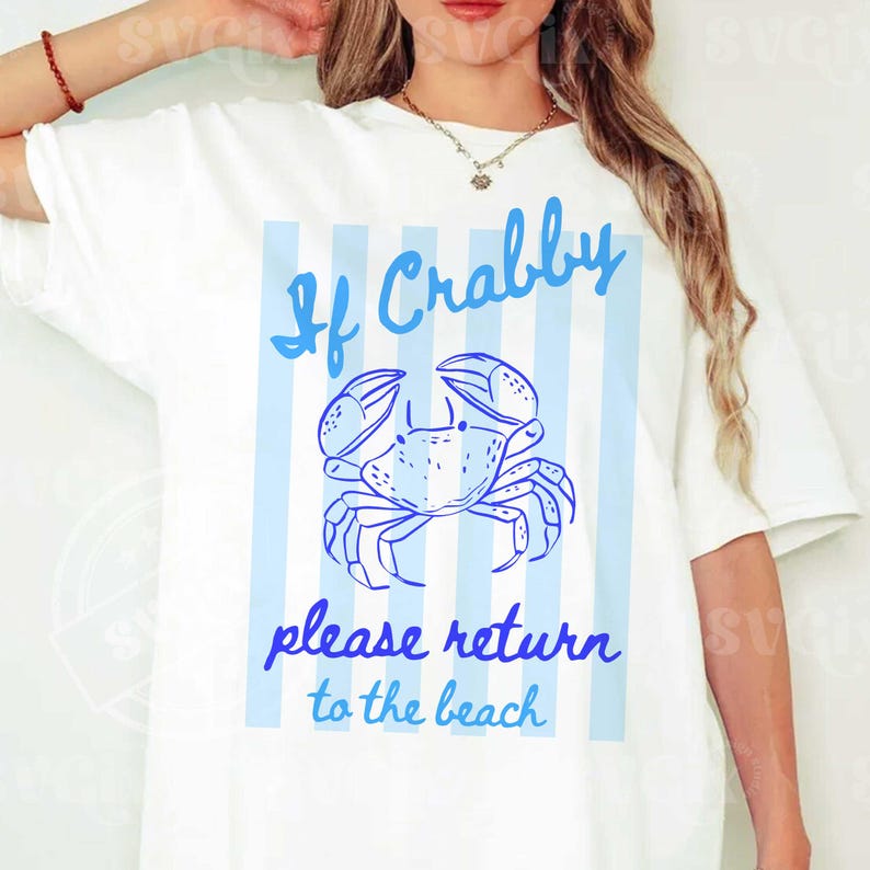 May include: White t-shirt with a blue crab graphic and the text "If Crabby please return to the beach." The design features a crab illustration with blue vertical stripes in the background. A casual, beach-themed tee.