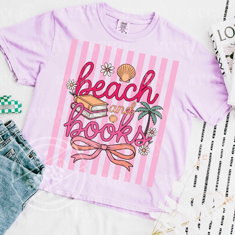 Puede incluir: Camiseta lila claro con la frase "beach and books" en rosa. El dise&ntilde;o incluye una concha, flores, una palmera y libros. La camiseta tiene cuello redondo y mangas cortas.