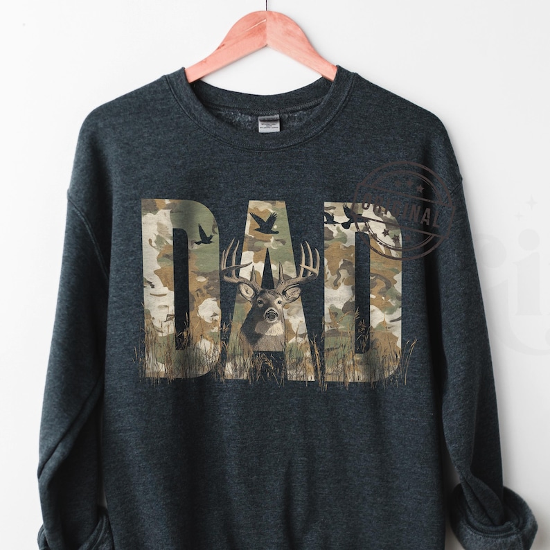 May include: A dark gray sweatshirt with the word "DAD" printed in camouflage pattern. The letter "A" features a deer with antlers in the center of the camouflage pattern.
