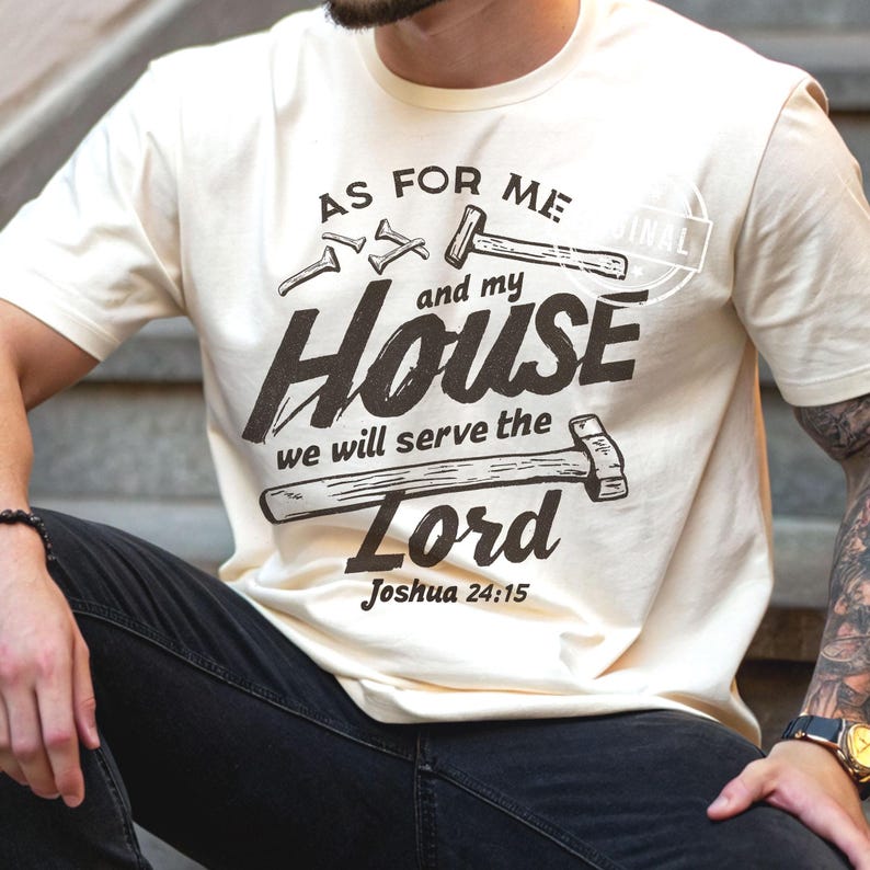 May include: Cream-colored t-shirt with the text "AS FOR ME and my HOUSE we will serve the Lord Joshua 24:15" in dark brown. The design includes illustrations of nails and hammers. The shirt is a casual wear item.