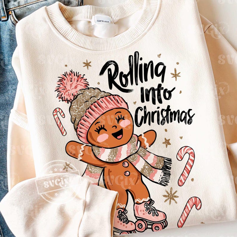 May include: Cream-coloured sweatshirt featuring a gingerbread person graphic wearing a pink and gold hat, scarf, and roller skates. The text "Rolling into Christmas" is above the gingerbread person, with candy canes and stars.