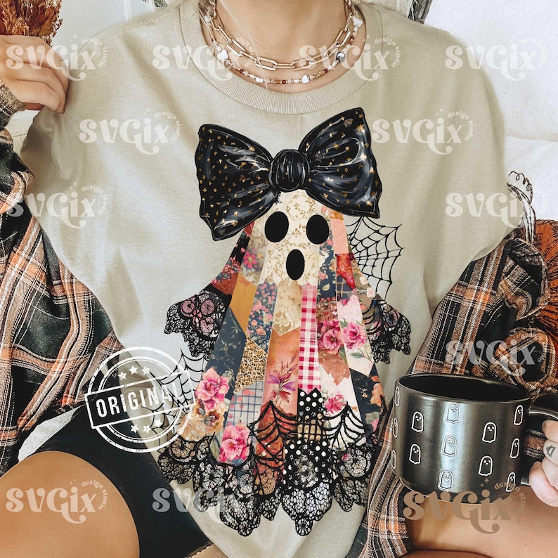 May include: Beige t-shirt featuring a patchwork ghost design with a black bow, lace, and spiderwebs. The ghost has three black eye holes and is made of floral and patterned fabrics. A black mug with ghost illustrations is also visible.