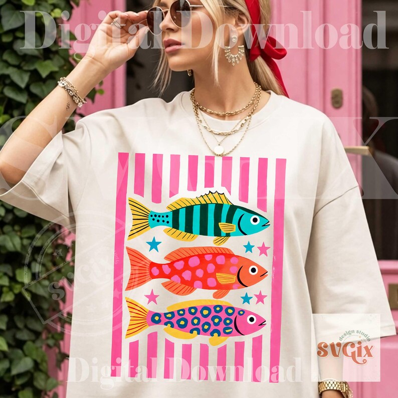 May include: Cream-colored t-shirt featuring a graphic of three colorful fish with pink vertical stripes. The fish are blue, red, and pink, with yellow and orange accents. The shirt has the text "Digital Download" and "svgix".