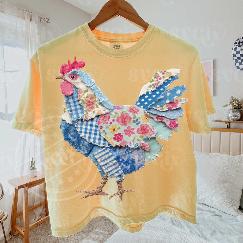 May include: Yellow t-shirt featuring a patchwork rooster design. The rooster is made of various patterned fabrics, including floral, gingham, and polka dots, in shades of blue, pink, and white. The shirt has a crew neck and short sleeves.