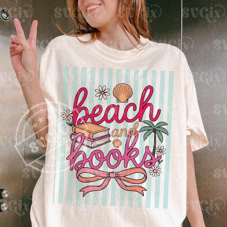 Puede incluir: Camiseta color crema con un gr&aacute;fico colorido. El gr&aacute;fico presenta las palabras "beach and books" en escritura rosa, junto con ilustraciones de una concha, flores, una palmera y un lazo. El fondo tiene rayas azul claro.