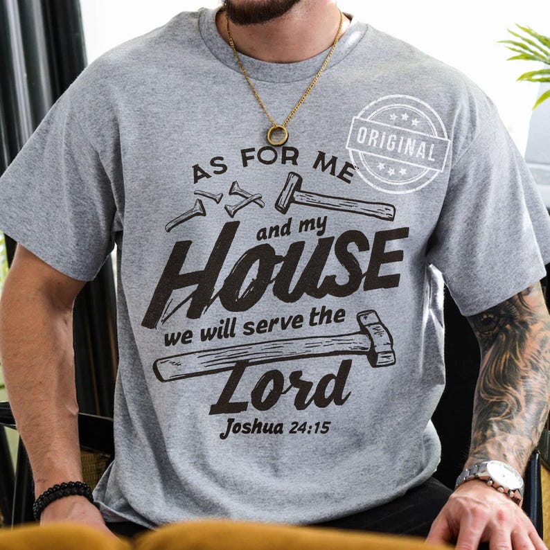 May include: A gray t-shirt with the text "AS FOR ME and my HOUSE we will serve the Lord Joshua 24:15" in black. The design includes illustrations of hammers and nails, with an "ORIGINAL" stamp.