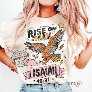 Puede incluir: Sudadera color crema con un &aacute;guila de alas extendidas, las palabras "RISE ON FAITH" y el vers&iacute;culo b&iacute;blico Isa&iacute;as 40:31. El dise&ntilde;o incluye estrellas, nubes y rayos. Un sello circular dice "ORIGINAL."