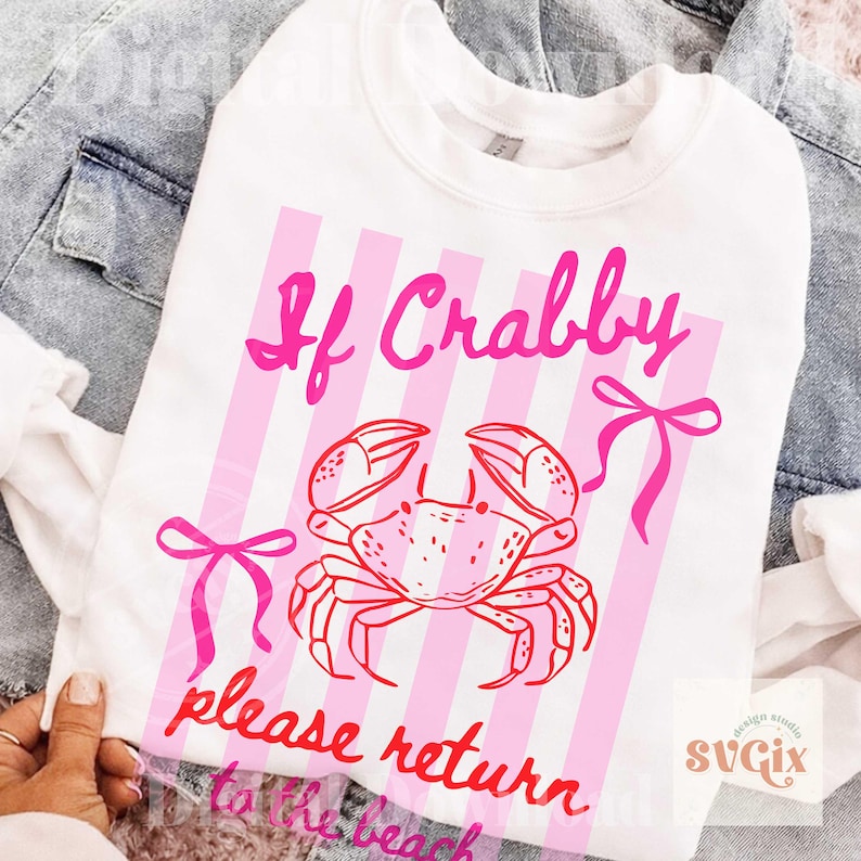 May include: White sweatshirt with a pink crab graphic and the text "If Crabby please return to the beach." The design includes pink vertical stripes and bows. A fun, beach-themed apparel item.
