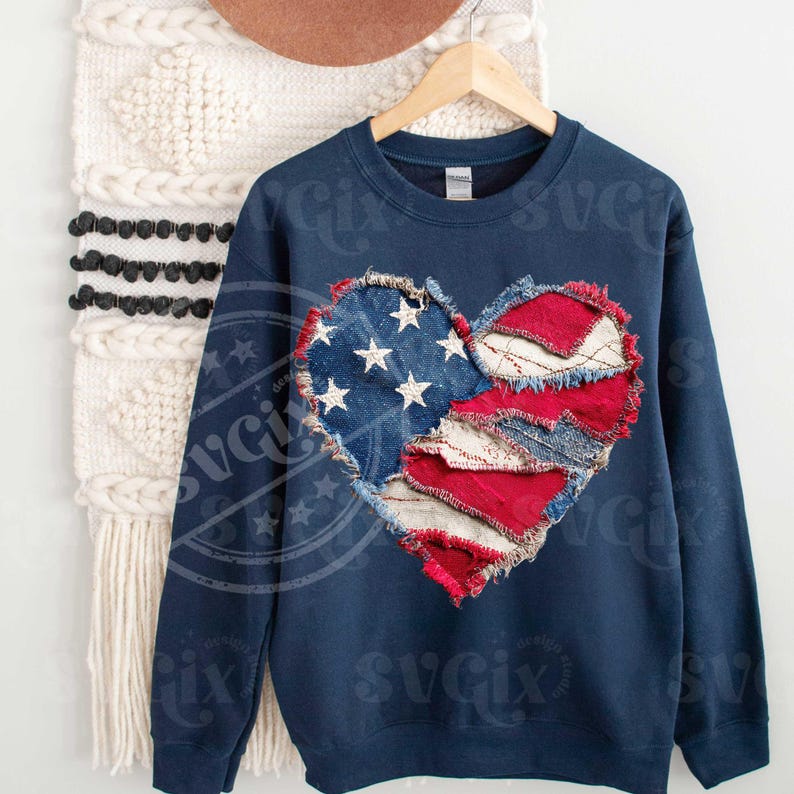 May include: Navy blue sweatshirt with a heart-shaped design made from denim and red fabric, resembling the American flag. The heart has white stars on a blue denim background and red and white stripes.