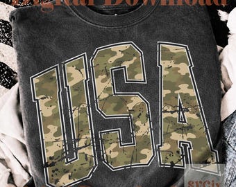 May include: Dark gray crewneck sweatshirt with the word "USA" in large, distressed, camouflage-patterned letters. The letters are outlined in white and have a vintage, worn look. The sweatshirt is a casual style.