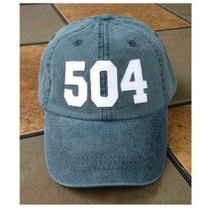 Puede incluir: Una gorra de béisbol de mezclilla azul con los números "504" bordados en blanco en la parte delantera.