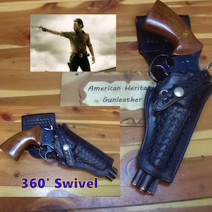 Op de afbeelding: Een zwart lederen holster met een mandvlechtpatroon en een 360-graden draaimechanisme, met daarin een revolver met een bruine houten greep. Een bord toont American Heritage Gunleather en een inzetstuk toont een persoon met een vuurwapen.