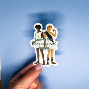 May include: A sticker with a white background featuring two figures in white tunics and sandals. The figures are standing side-by-side and holding cups. The text "Name one hero who was happy" is written in teal cursive.