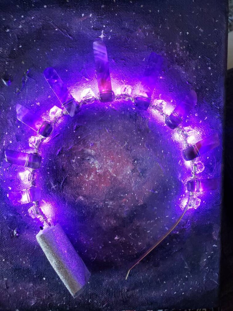 May include: A purple crystal headband with embedded LED lights, creating a glowing effect. The headband is made of metal and has a silver finish.