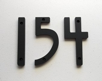 May include: Black metal house numbers 1, 5, and 4. The numbers are attached to a white wall.