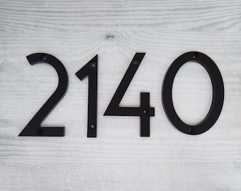 May include: Black metal house numbers, 2140, mounted on a light wood surface.