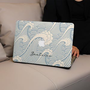May include: A laptop computer with a blue and white wave pattern design. The laptop has the name "Beatrice" written on it.