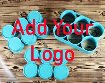 Puede incluir: Un conjunto de moldes de silicona azul para hacer velas o jabón. Los moldes están dispuestos en círculo con el texto "Add Your Logo" en letras rojas en el centro.