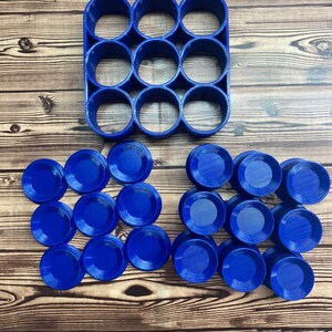 Op de afbeelding: Een blauwe plastic mal met 12 ronde uitsparingen en 18 blauwe plastic cirkels die in de mal passen.