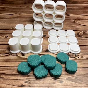 May include: An assortment of white 3D-printed objects, including cylindrical and oval shapes, and teal, textured, round objects. The objects are arranged on a wooden surface, showcasing various shapes and textures.