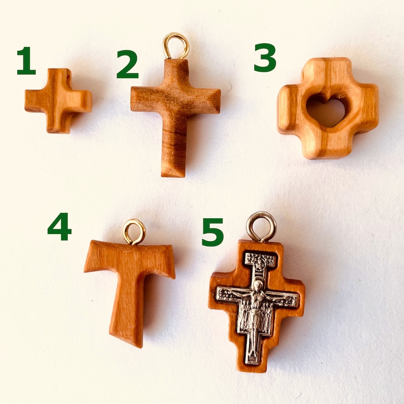 May include: Five different wooden cross pendants, each with a unique design. The crosses are made of light brown wood and have a natural finish. The pendants are numbered 1 through 5.