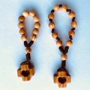 May include: Two olive wood rosaries with brown cords and heart-shaped cross pendants.