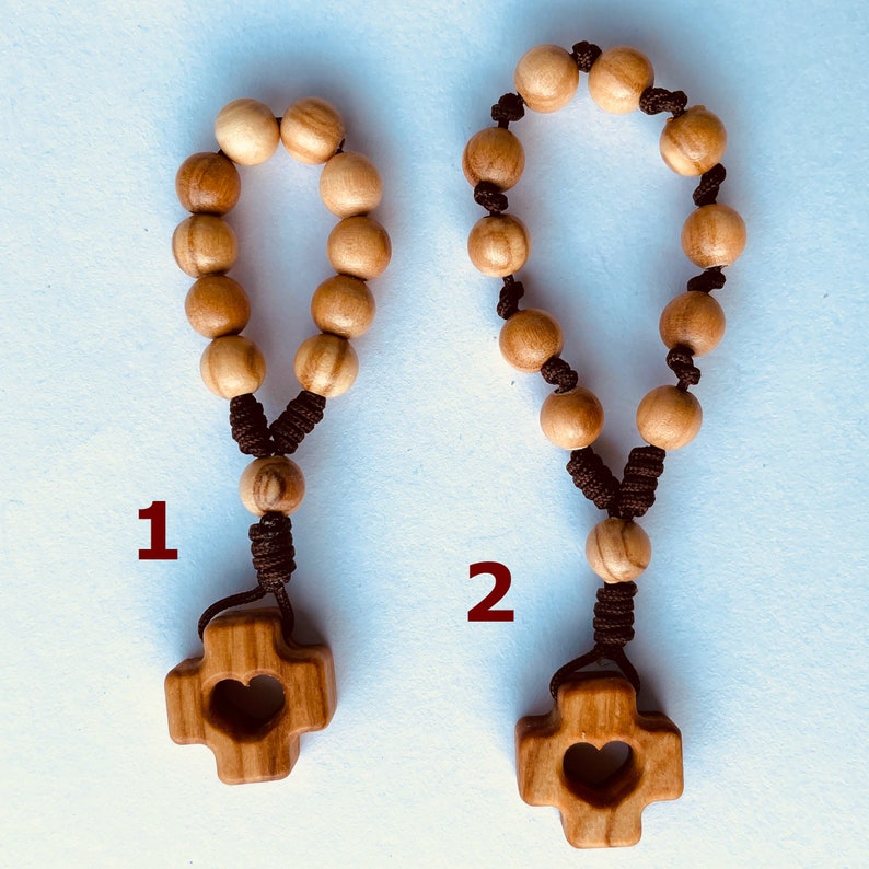 May include: Two wooden rosaries with brown cords and heart-shaped cross charms. The rosary on the left has a number "1" next to it, and the rosary on the right has a number "2" next to it.