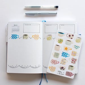 May include: A sheet of stickers featuring various colorful mugs with different patterns. The stickers are arranged in rows and columns on a white background. The text "Valley of Paper" is printed in the bottom right corner of the sheet.