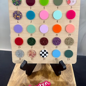 May include: A wooden display board with the text "Key chains" and a selection of colorful keychains. The keychains are arranged in rows and columns, with a variety of colors and patterns. Below are personalized keychains with names.